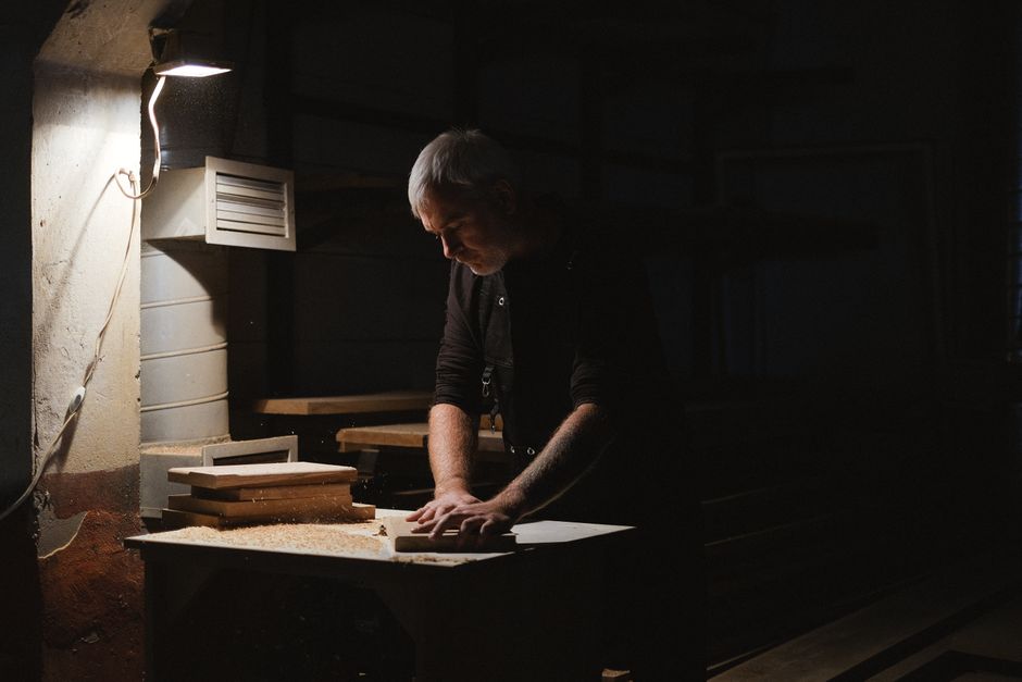 A master craftsman carefully shaping wood in a custom furniture workshop
